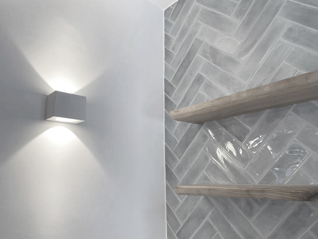 Wanddetail mit grauen Fliesen, Holzregalen und Wandleuchte